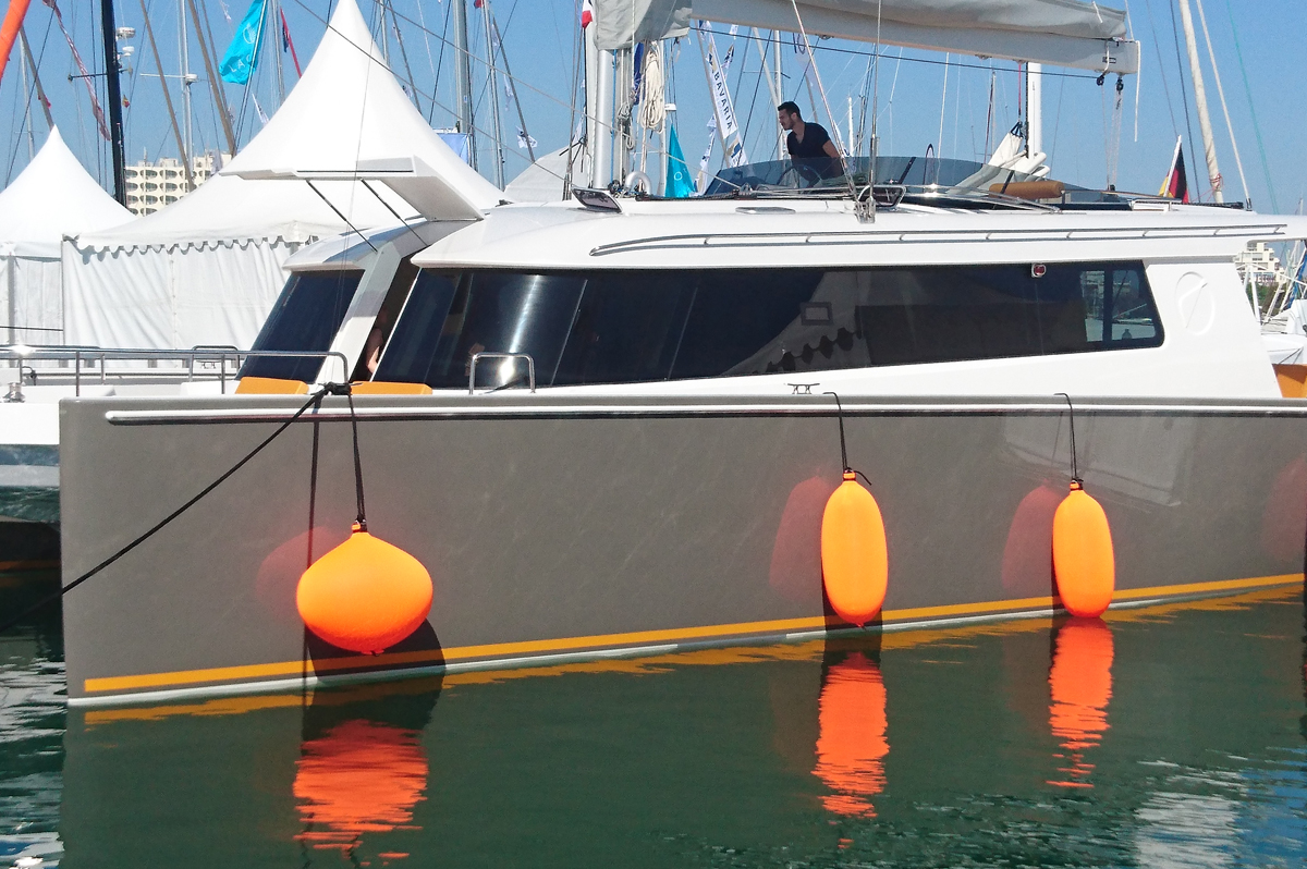 Orange spherical and cylindrical Fendertex fenders on catamaran